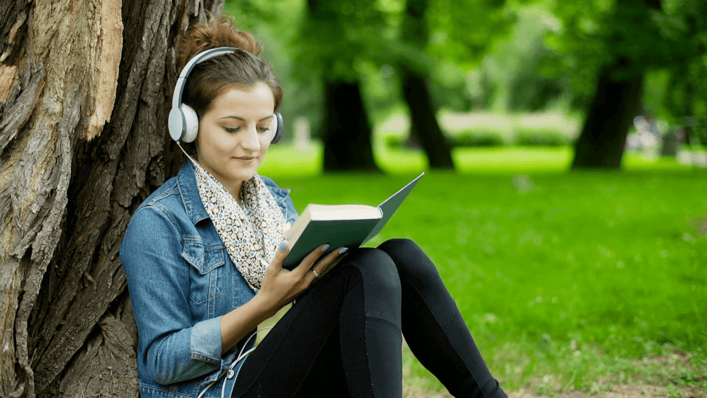 girl-listening-music-on-headphones-and-reading-book-min